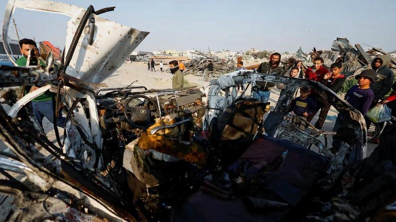 Palestinians inspect the site of an Israeli airstrike targeting a police vehicle in the central Gaza Strip