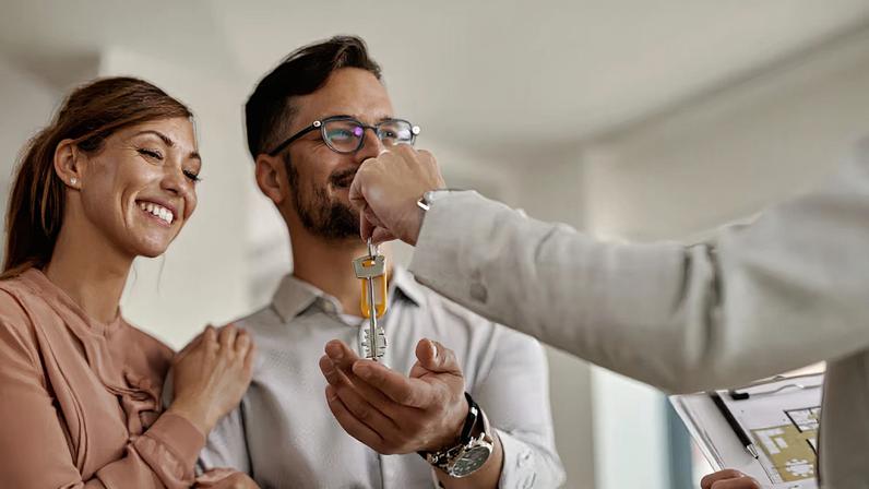 Close-up of a real estate agent giving to a couple keys of their new home.
