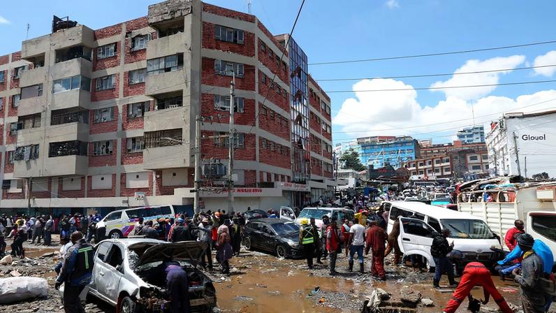 People stand around destroyed vehicles following flash floods caused by heavy rainfall in the Grogan area, in Nairobi