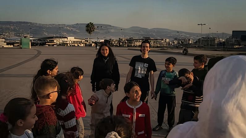 Unos niños juegan en un campamento de refugiados de Beirut con los bombardeos israelíes sobre la ciudad de fondo, este martes.
