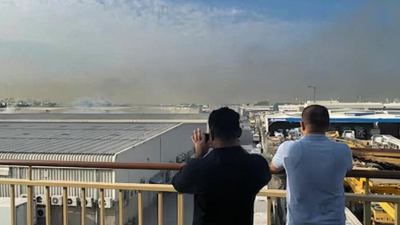 Dos ciudadanos toman fotos del humo que sale de un incendio en la zona industrial de Al Quoz en Dubái. Este, según las autoridades, fue causado por la interceptación de un misil el pasado 13 de marzo.