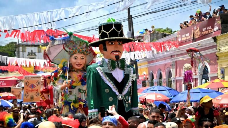 Imagem de uma multidão acompanhando um boneco gigante no carnaval de Olinda.