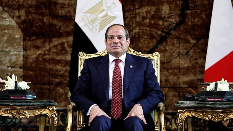 Abdel Fattah al-Sisi sits in a golden chair in front of the Egyptian flag.