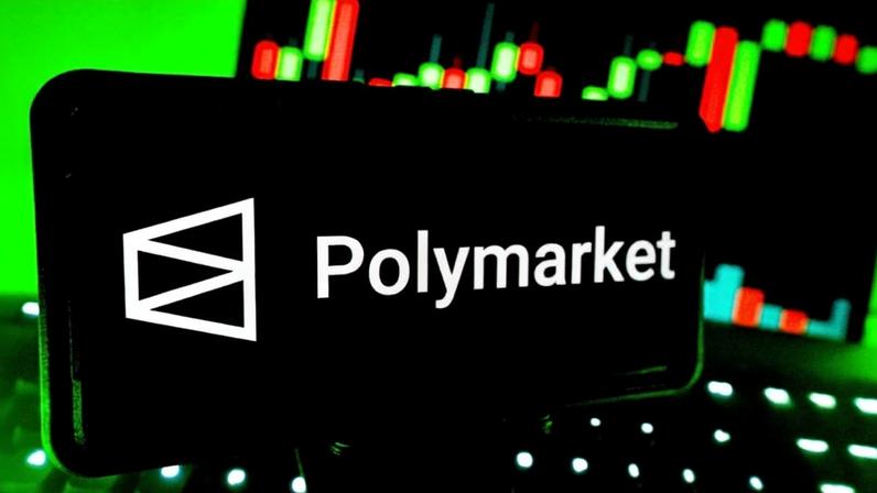 Smartphone mostra logo da plataforma de previsão Polymarjet; ao fundo, um gráfico de mercado financeiro