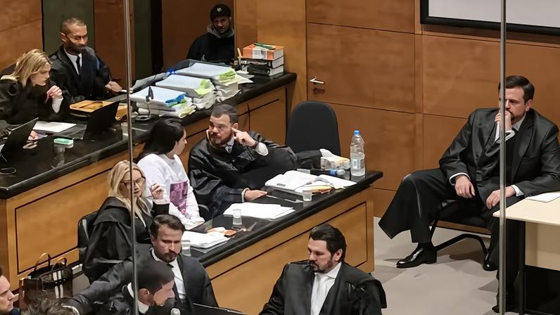 Vestindo camisa branca com imagem de Henry, Monique Medeiros permanece sentada durante sessão