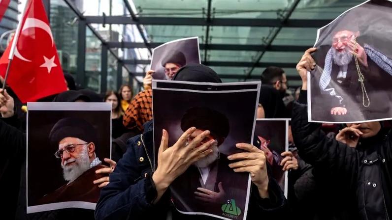 Protestors hold printed images of Ayatollah Ali Khamenei and a Turkish flag.