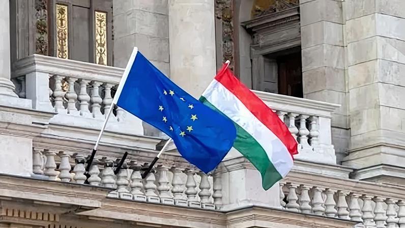 Flags of the European Union and Hungary flying from poles outside an ornate building in the centre of Hungarian capital city of Budapest