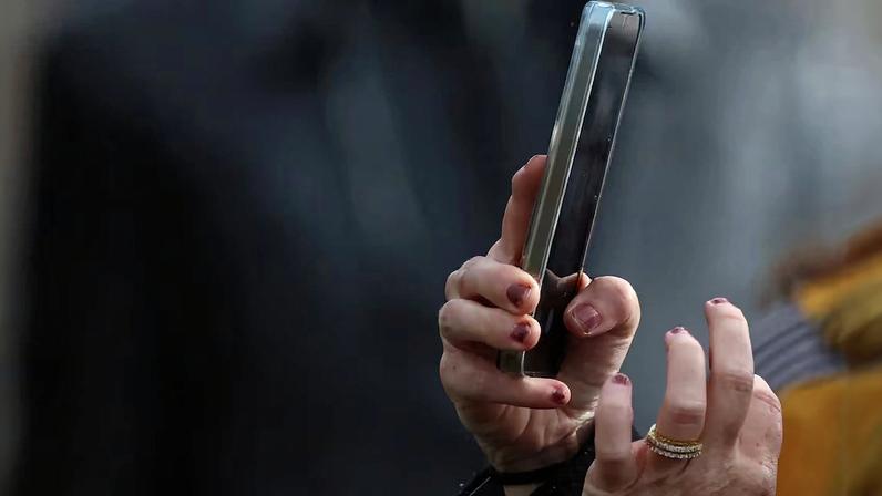 A woman uses a smartphone to take a photograph in Liverpool