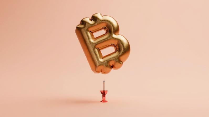 Balão dourado em forma de "B" flutua sobre fundo pêssego, equilibrado delicadamente em uma ponta de um pin vermelho.
