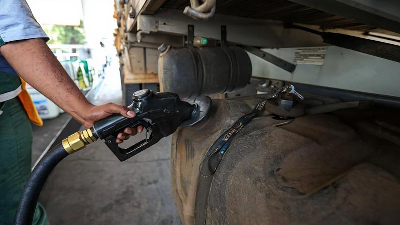 Imagem de um frentista abastecendo um caminhão com diesel