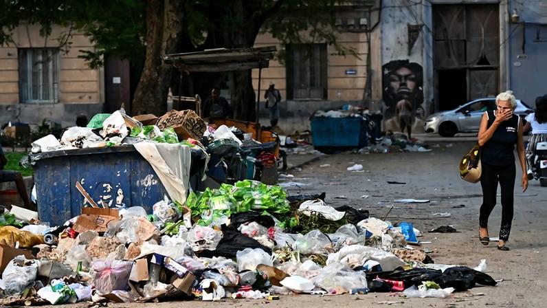 A woman covers her nose as she walks past garbage on a street in Havana, Cuba on Dec. 4, 2025.