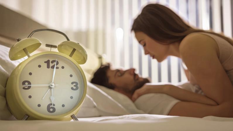 The clock on the background of the couple in the bed