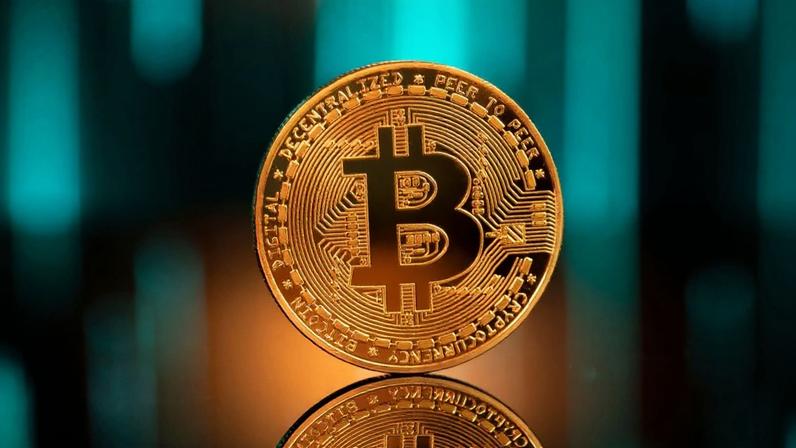 moeda dourada de bitcoin;ao fundo, luzes azuis