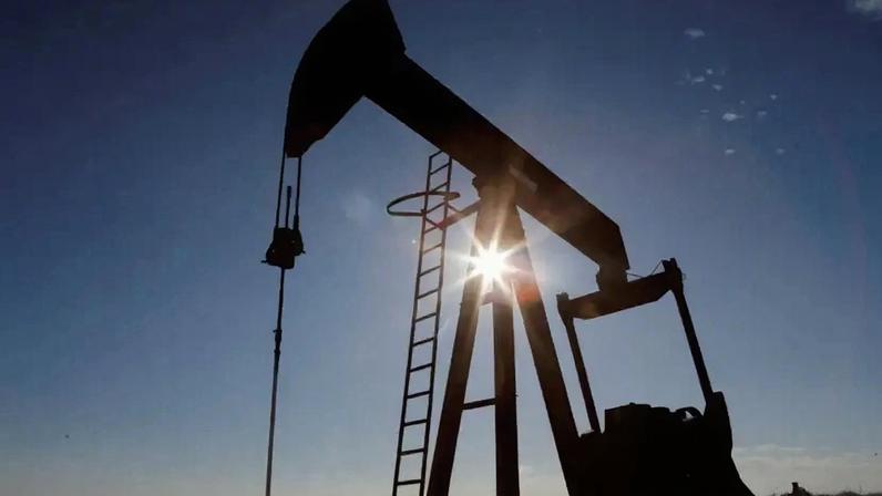 Petroleira em funcionamento aparece na foto com contraste ao pôr do sol