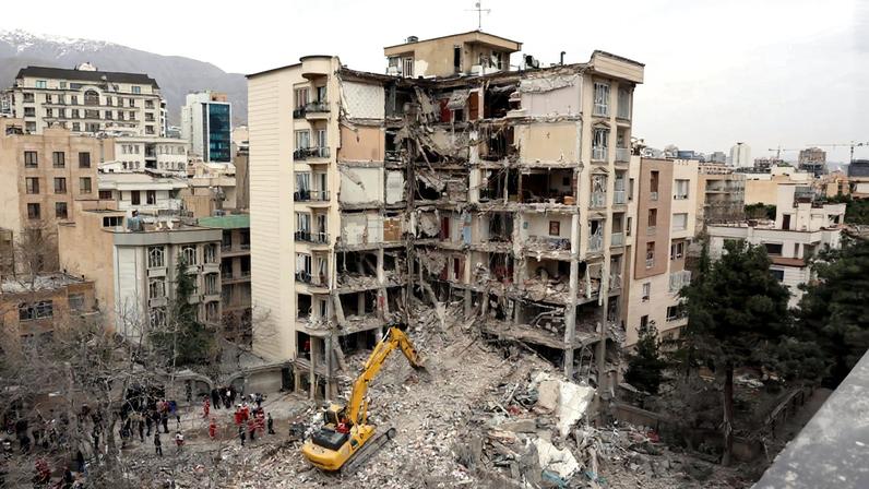 Uma escavadeira remove os escombros de prédios residenciais destruídos no norte de Teerã, em 23 de março de 2026