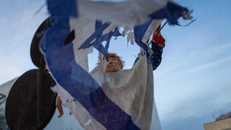Manifestante segura uma bandeira israelense rasgada durante o protesto semanal contra a guerra na Praça HaBima, em Tel Aviv