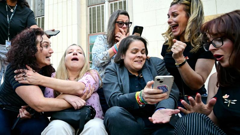 Laura Marquez-Garrett (3ª à direita, blazer cinza), advogada dos demandantes do SMVLC (Centro Jurídico para Vítimas de Mídias Sociais), reúne-se com familiares das vítimas enquanto reagem à notícia de que o júri considerou a Meta e o YouTube culpados no julgamento sobre vício em mídias sociais