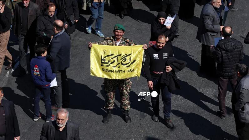 Um militar segura uma faixa enquanto iranianos participam de uma manifestação contra os EUA e Israel