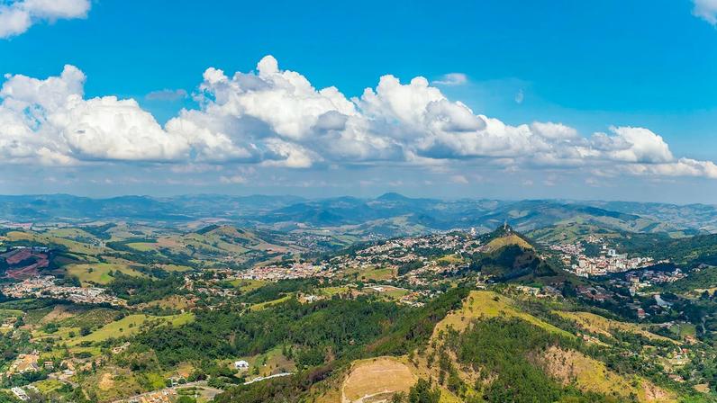 Vista aérea de cidade do interior paulista, com áreas verdes e céu azul, em dia ensolarado