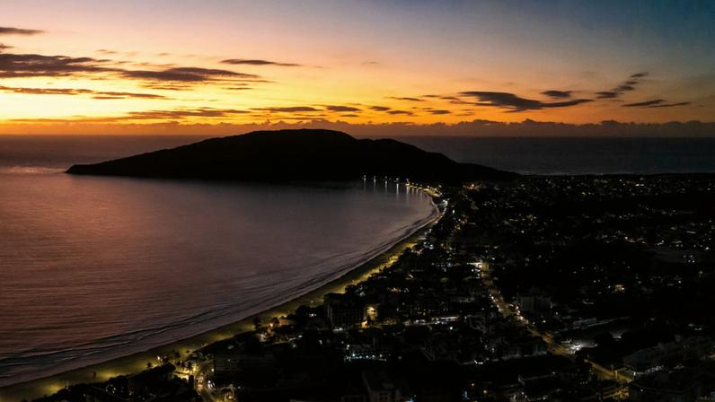 Vista panorâmica de Florianópolis ao entardecer, com a Ponte Hercílio Luz ao fundo