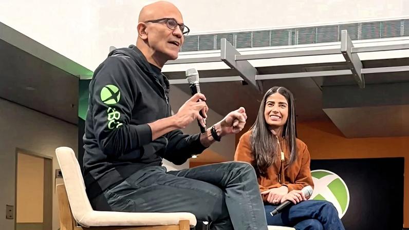 Satya Nadella sits with Asha Sharma in a meeting.