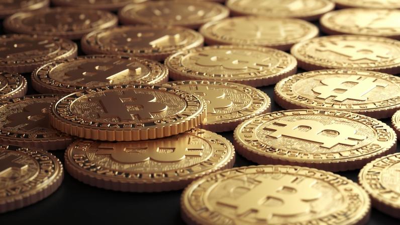 Moedas Douradas de Bitcoin em cima de uma superfície preta