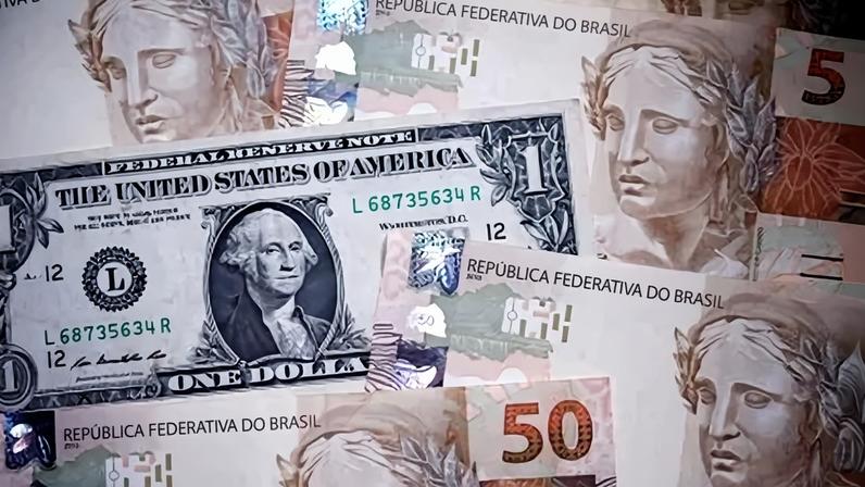 Notas de dólares e de reais em foto de ilustração