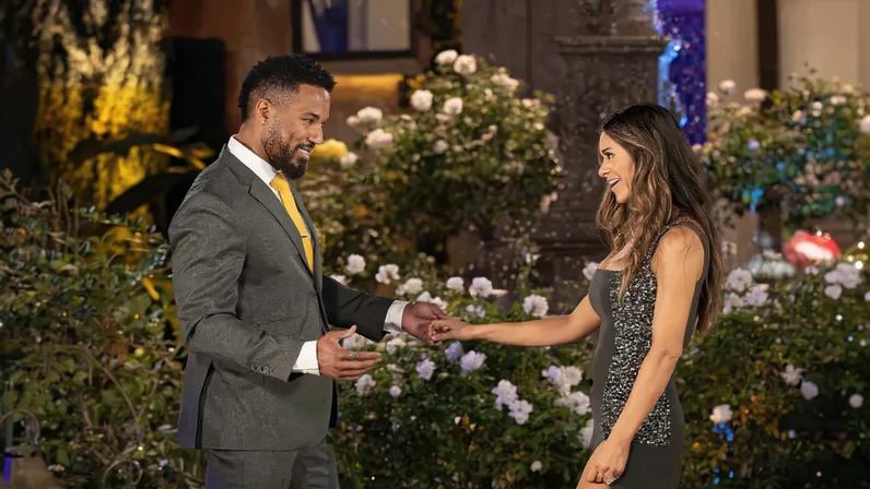 Rod and Taylor Frankie Paul holding hands and smiling at each other at night, surrounded by illuminated rose bushes.