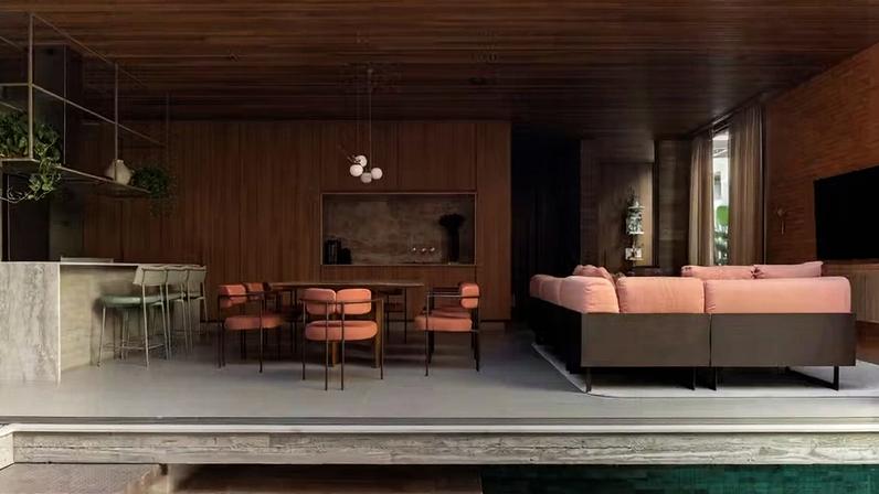 LIVING | Integrado e aberto para o pátio interno com piscina, o living tem sofá Oslo, de Giorgio Bonaguro, na área do estar. No jantar, mesa Fio, de Jacqueline Terpins, com cadeiras Sophi, do estúdio Goia Design. Luminária pendente Sabiá 4, de Cristiana Bertolucci. Paredes revestidas de painéis de MDF Freijó Puro, da Duratex, executados pela Gerizim Móveis Planejados. Forro de cumaru, da Portaco. Piso de porcelanato Via Durini Grey, da Portobello