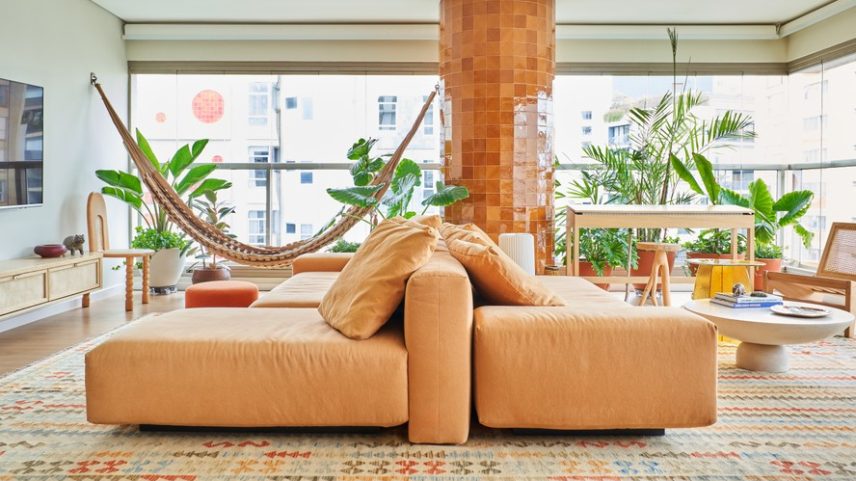 LIVING | O sofá-ilha em tom terroso do Estúdio Ninho para a Carbono Design combina com o pilar, antes cinza, agora revestido de azulejos alaranjados artesanais da Colormix, uma referência ao movimento das águas dos rios amazônicos. O rack e o piano têm desenho do escritório, executados pela Frank Móveis. Poltrona da Casa Atica. Tapete da by Kamy. O paisagismo feito pela Musgo traz frescor ao ambiente