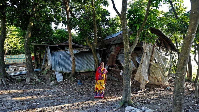 Hasina Begum stands in front of her house that got destroyed in multiple flash floods occurring in 2022. She temporarily moved to the industrial town of Narayanganj to earn the money needed to repair the house and to make up for the loss of crops.