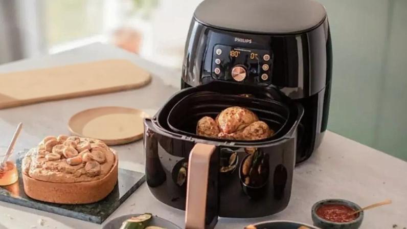 Fritadeira elétrica na bancada da cozinha com vários alimentos ao redor