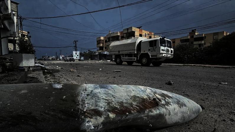 Forças de segurança da ONU baseadas no Líbano (Unifil) passam pelos restos de munição após um ataque aéreo israelense
