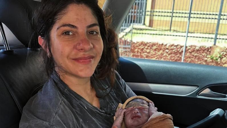 Lais segurando o filho logo após o nascimento dentro de um veículo