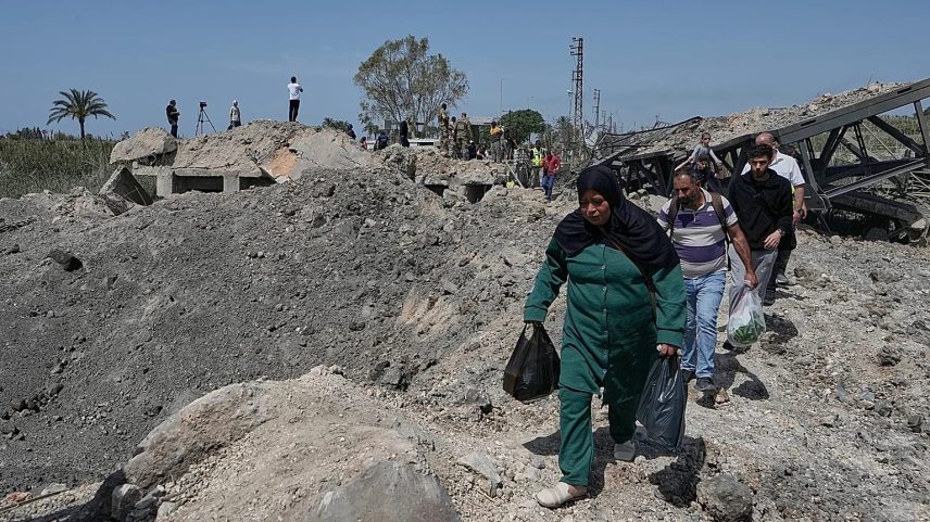 People cross on foot through a crater following an Israeli air strike that destroyed the Qasmiyeh Bridge near the coastal city of Tyre, 16 April, 2026