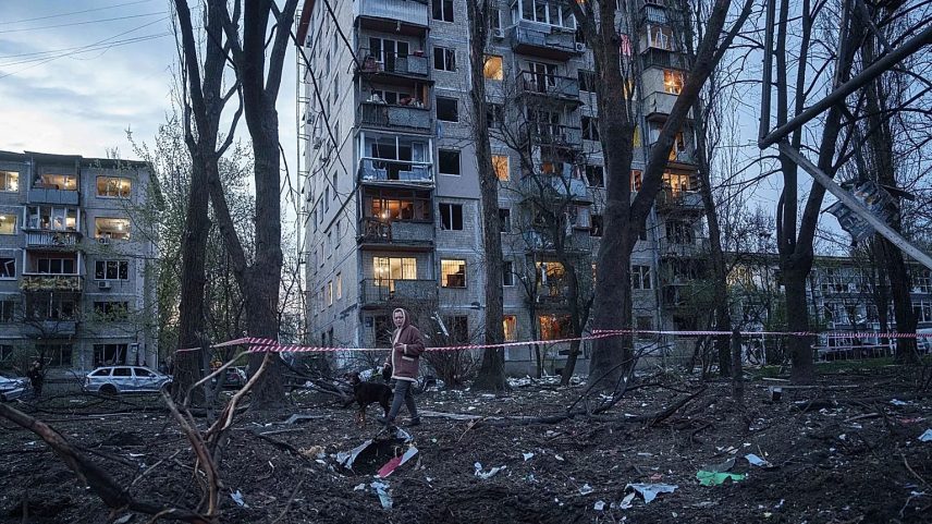 A woman with a dog walks among the rubble of a house damaged after a Russian strike on residential area in Kyiv, Ukraine, on Thursday, April 16, 2026.