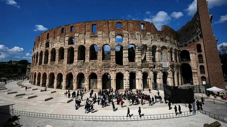 People walk in the new outdoor space created with travertine marble around the Colosseum during it's inauguration in Rome, Tuesday, March 17, 2026