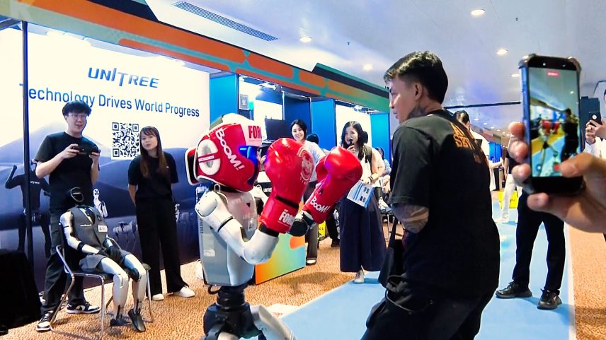 Humanoid robot "Unitree G1" making boxing movements and punching visitor Russel Lupang, from Malaysia.