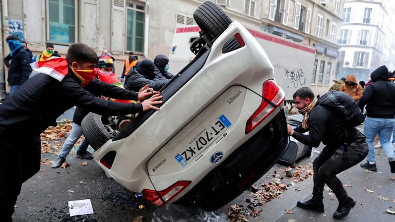 FILE - Demonstrators turn a car over during a protest against the shooting at the Kurdish culture centre in Paris, 24 December 2022.