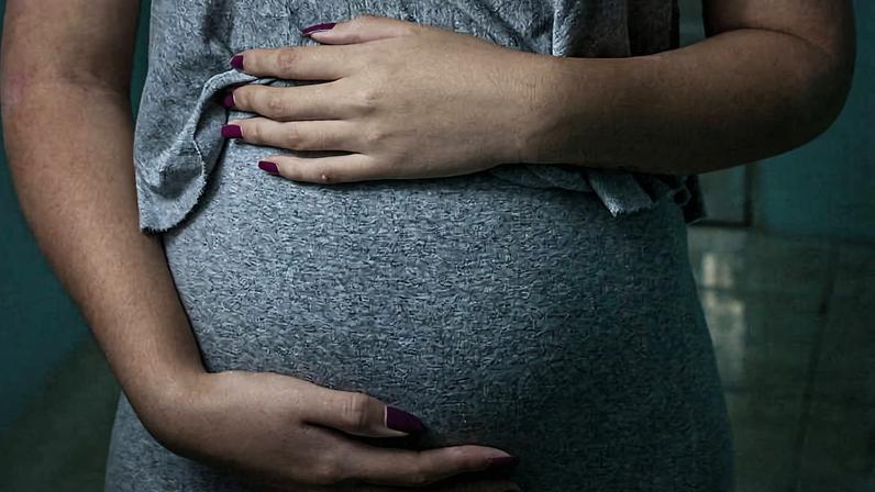Jovem grávida com as mãos sob a barriga