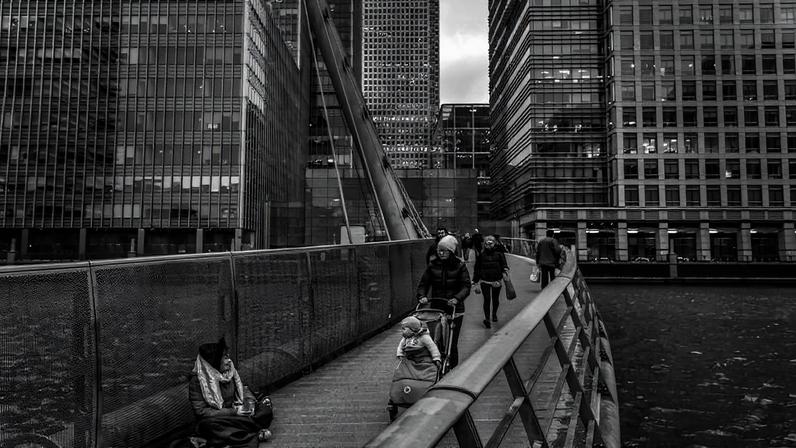Mulher pede esmola em ponte para pedestres em Canary Wharf, região de Londres que concentra sedes de grandes bancos e empresas - Lalo de Almeida - 12.jul.19/Folhapress