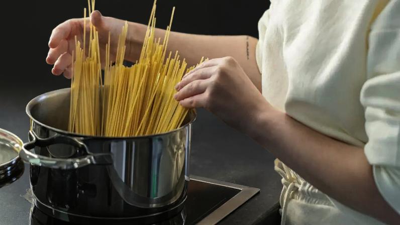 Mulher na cozinha preparando macarrão