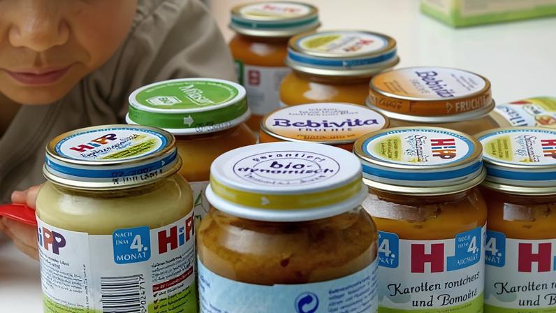A baby next to jars of HiPP baby food