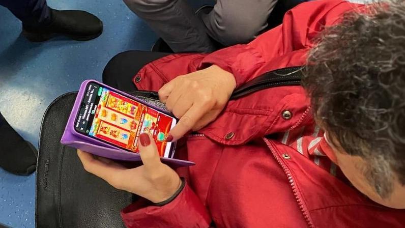 Mulher aposta em cassino virtual no celular enquanto se desloca no transporte público