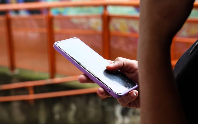 Jovem usa telefone celular em escola de São Paulo