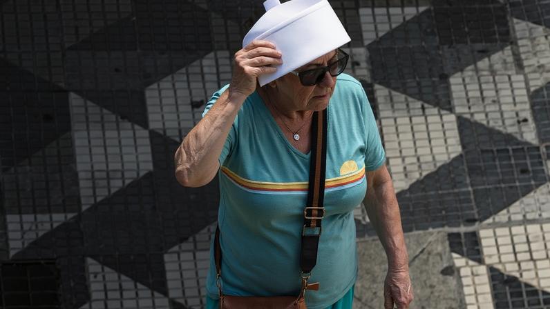 Mulher caminha pelo viaduto do Chá, em São Paulo, e usa papel para se proteger do sol