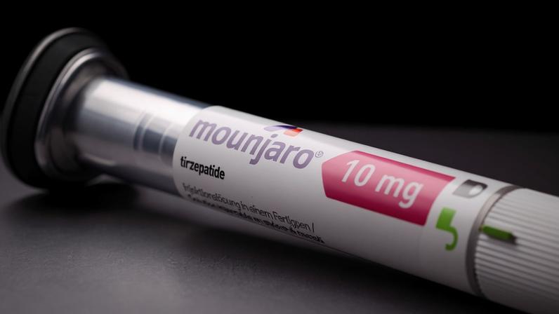 Caneta de insulina Mounjaro com dose de 10 mg, posicionada sobre superfície cinza com fundo preto. Rótulo mostra nome do medicamento e dosagem.