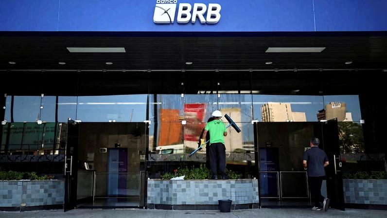 Trabalhador limpando fachada do BRB em Brasília