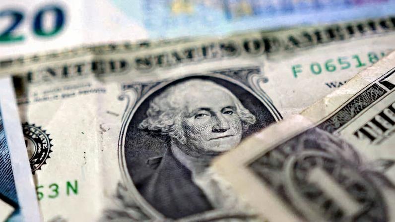 Notas de dólar americano sobrepostas, com destaque para o retrato de George Washington na nota de um dólar. Outras cédulas parcialmente visíveis ao fundo, incluindo uma nota de vinte dólares.