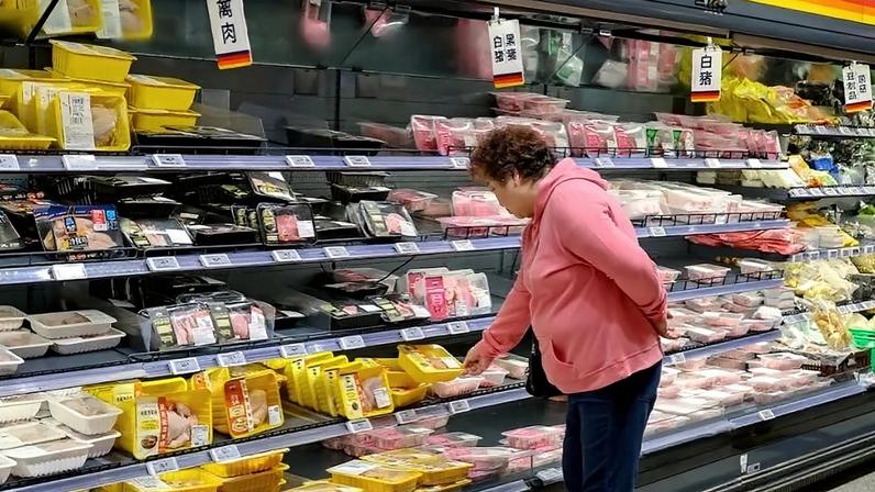 Uma cliente escolhe carne de porco em um supermercado em Xangai